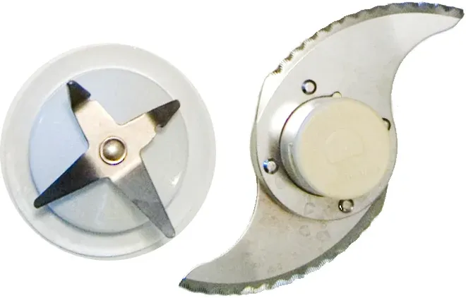 A blender's four-pronged cross blade on a round base next to a food processor's curved, serrated S-shaped chopping blade