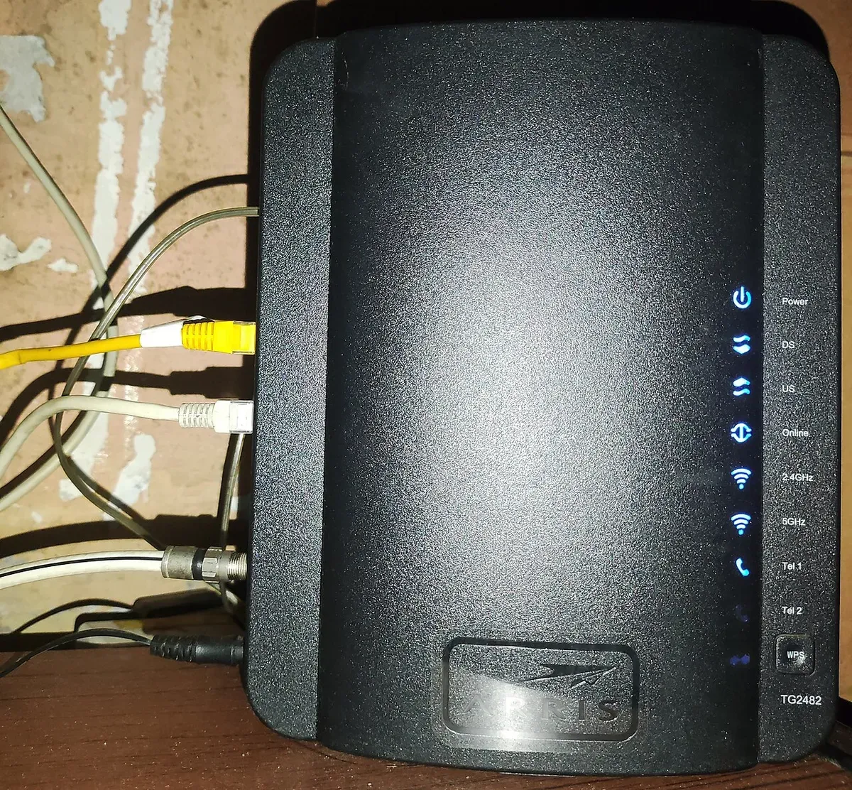 A black ARRIS TG2482 cable gateway with status lights for power, downstream, upstream, online, 2.4 GHz and 5 GHz Wi-Fi, and phone lines