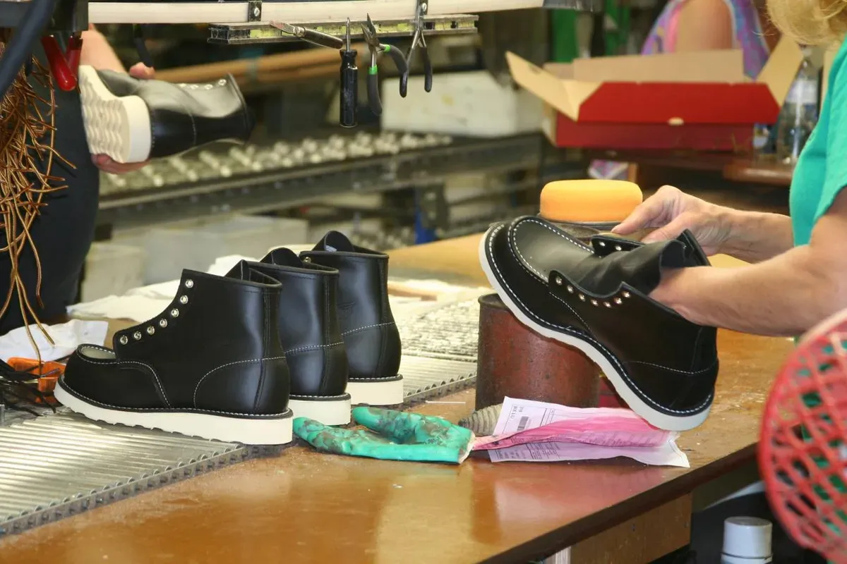 Workers assembling black Red Wing moc toe boots on a factory workbench